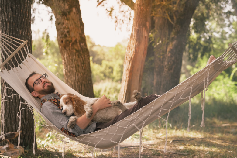 a guy and his dog sleeping peacefully in a hammock